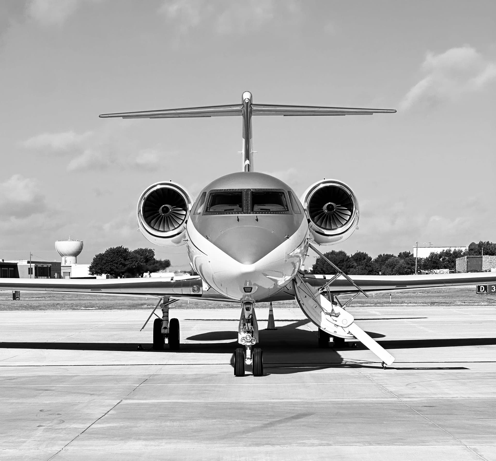 Private jet on tarmac viewed from front with engines and deployed stairs